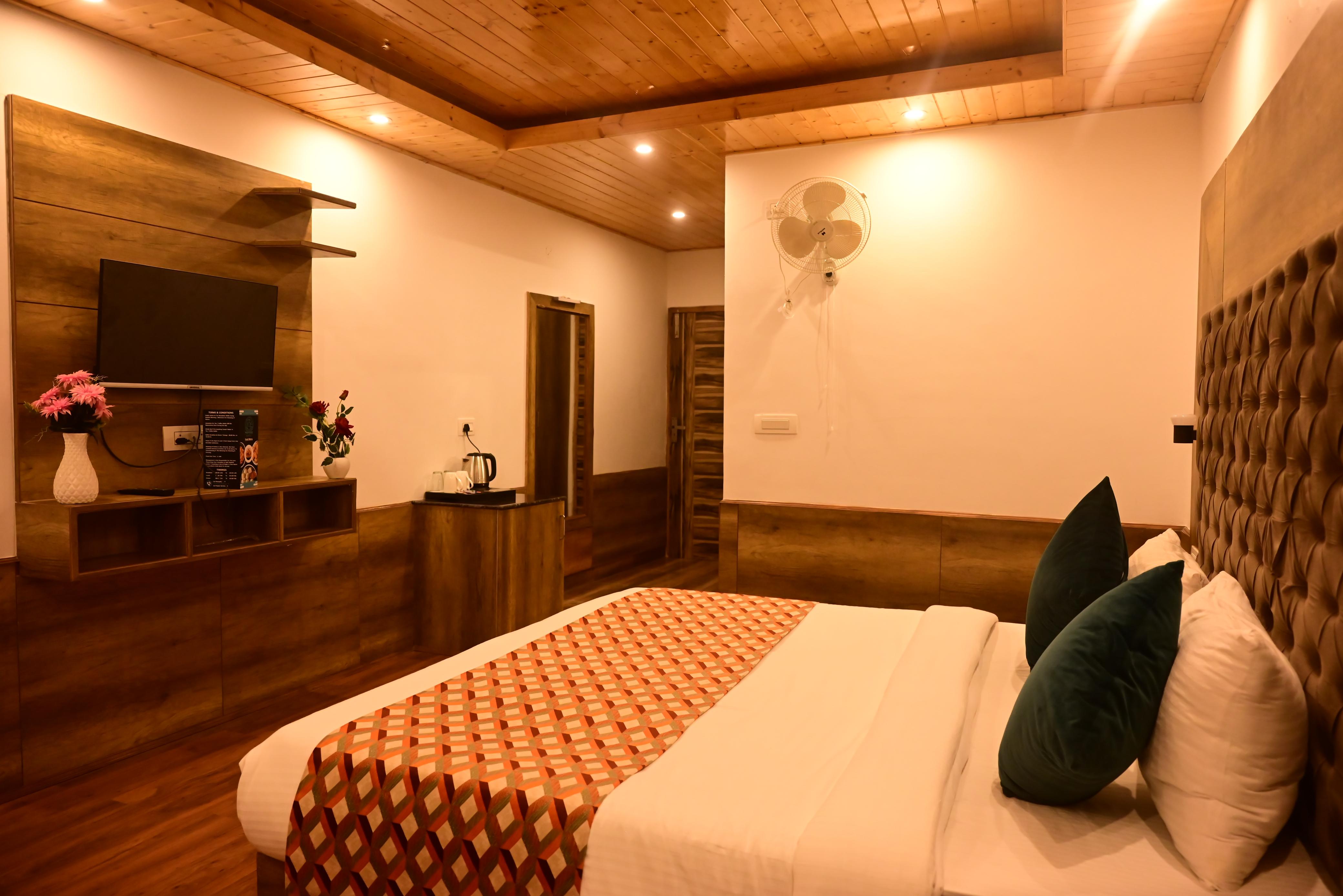 Manali hotel bedroom with bed, television and sitting area